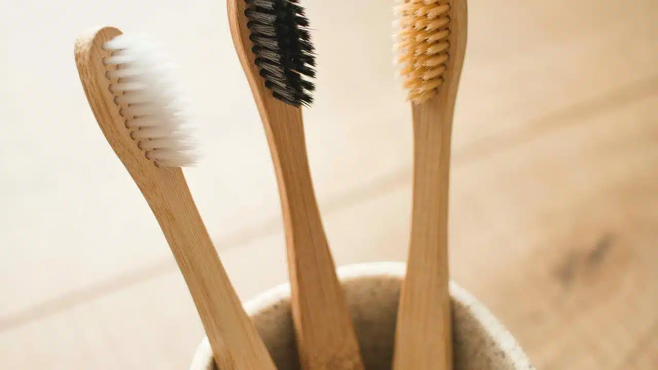 A close-up of three bamboo toothbrushes with different bristle colors.