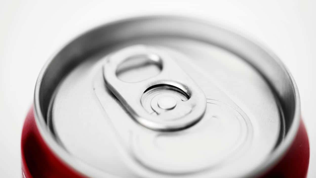 A close-up of a red aluminum can’s pull tab.
