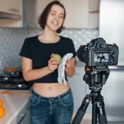 A woman filming a cooking video in a kitchen.