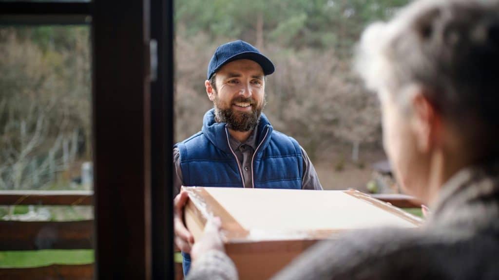 A deliveryman hands off a package to a senior woman.