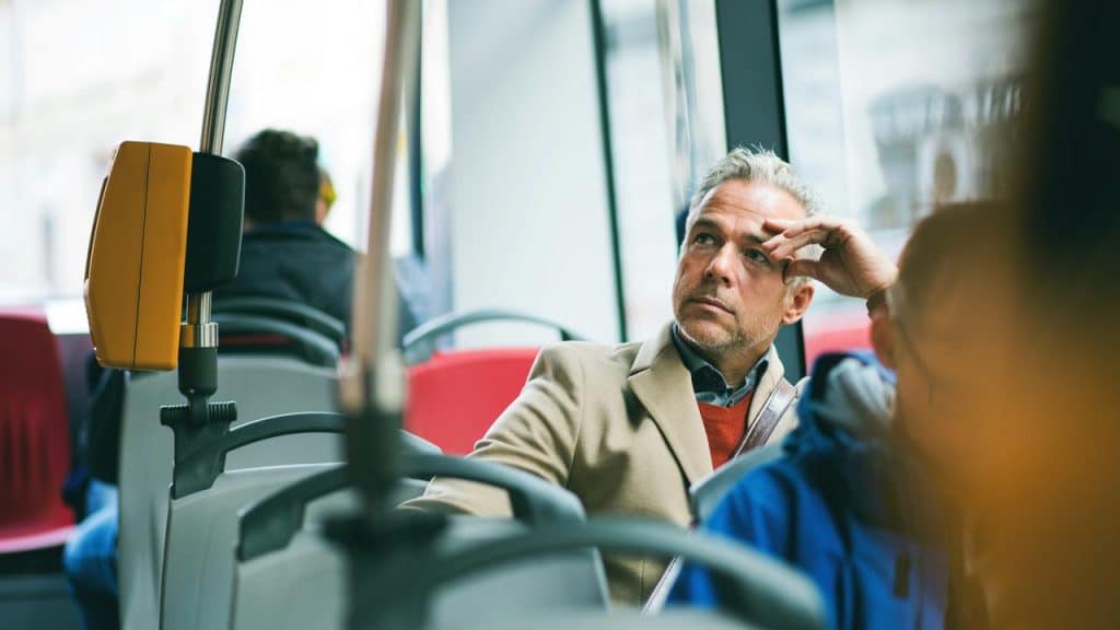 A man looking tired as he rides the bus to work.