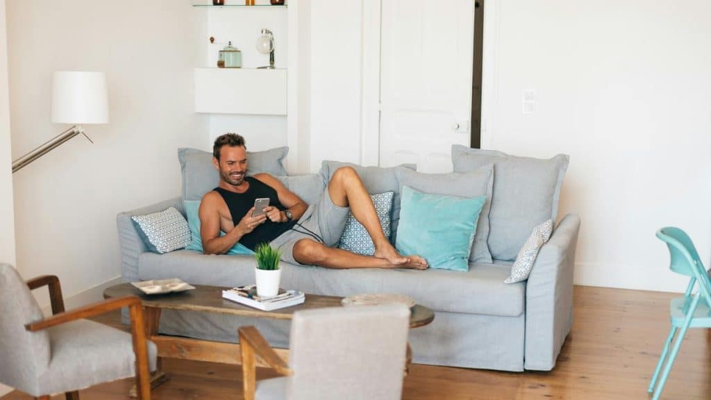 A man sitting on a couch while using his phone.