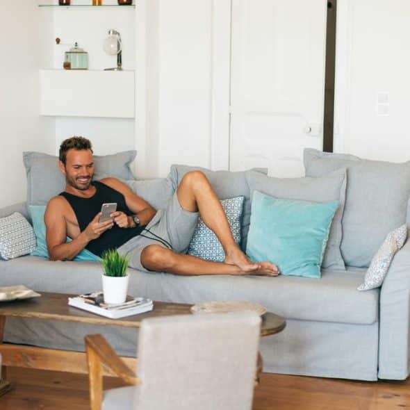 A man sitting on a couch while using his phone.