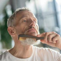 A man combing his gray beard.