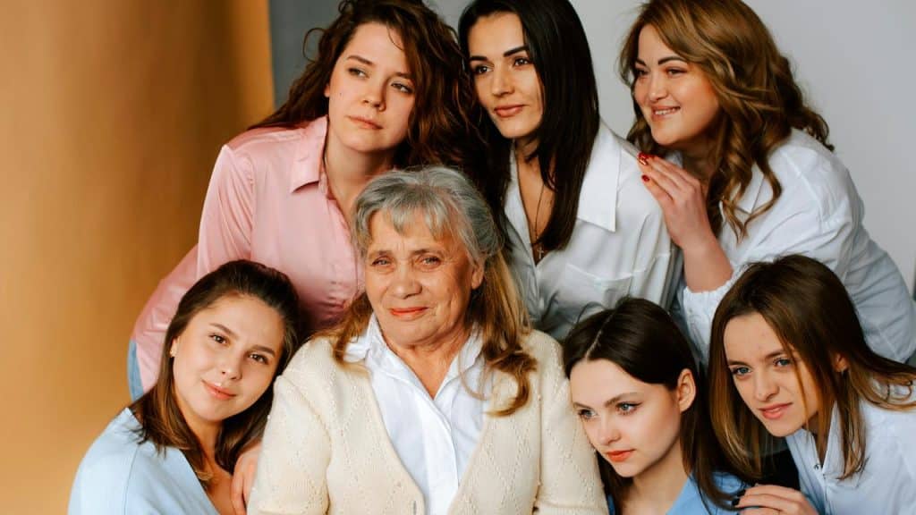 An elderly woman surrounded by six younger women posing for a photo.