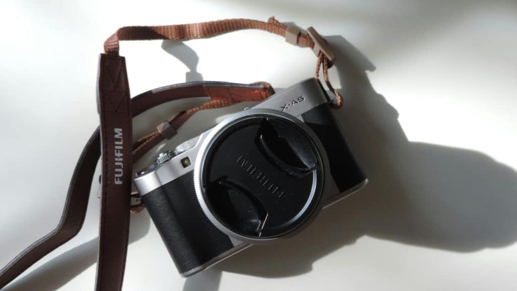 A Fujifilm X-A5 camera with a brown strap on a white surface.