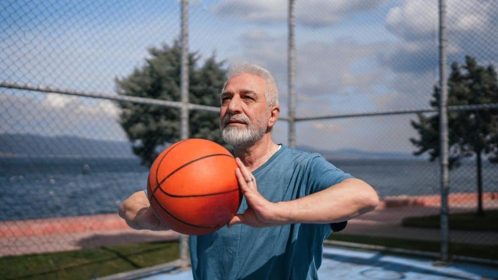 An older man preparing to shoot a basketball on an outdoor court.