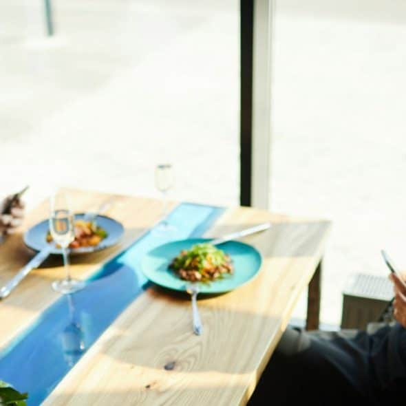 A man and woman sit at a table, both looking at their phones.