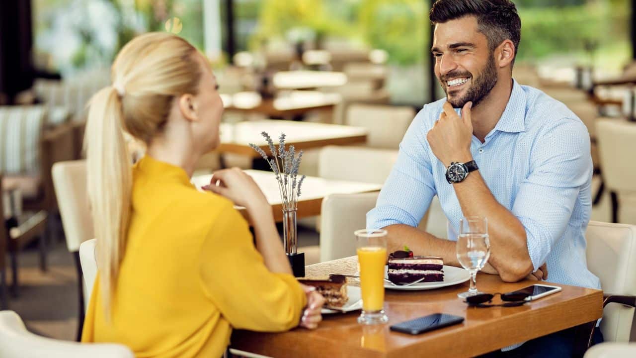 A happy couple smiles at each other while having dessert at a restaurant.