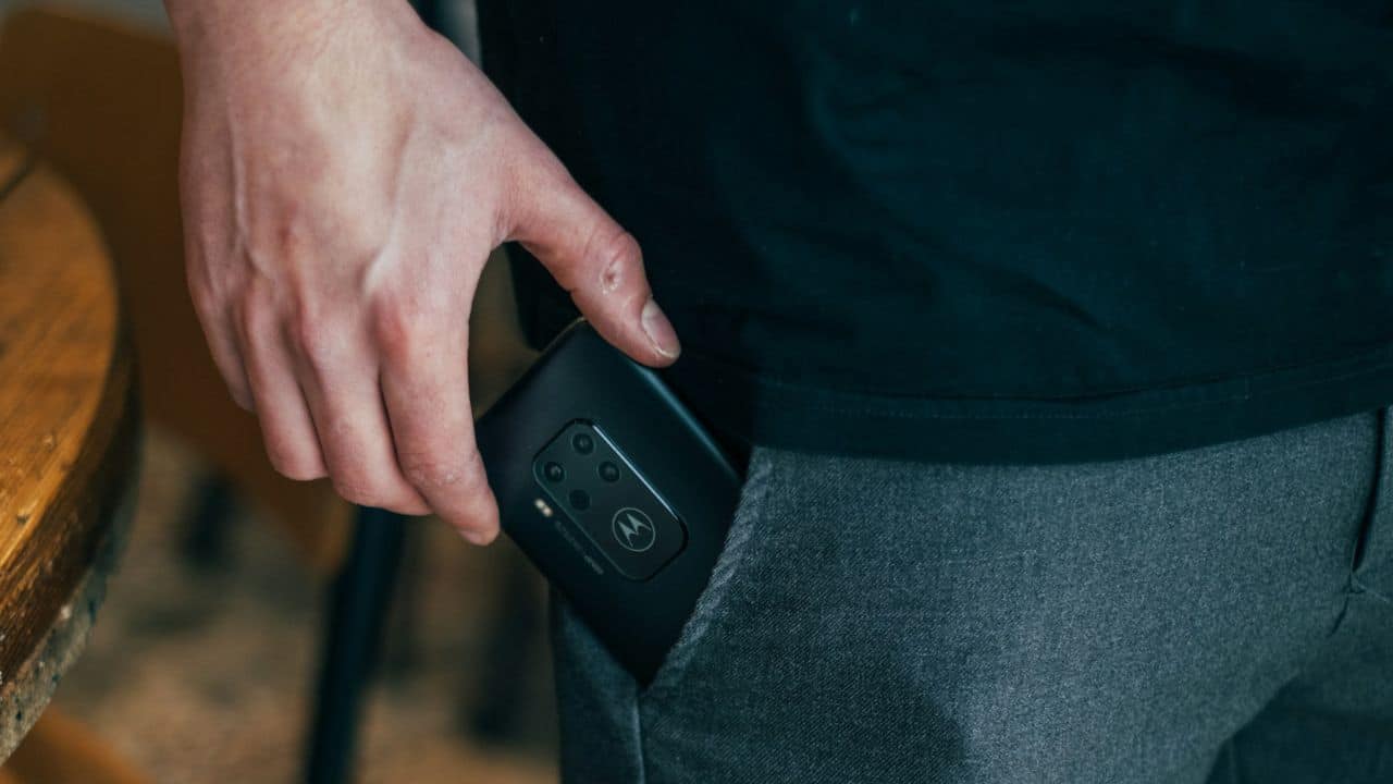A person's hand slides a phone into their back pocket.