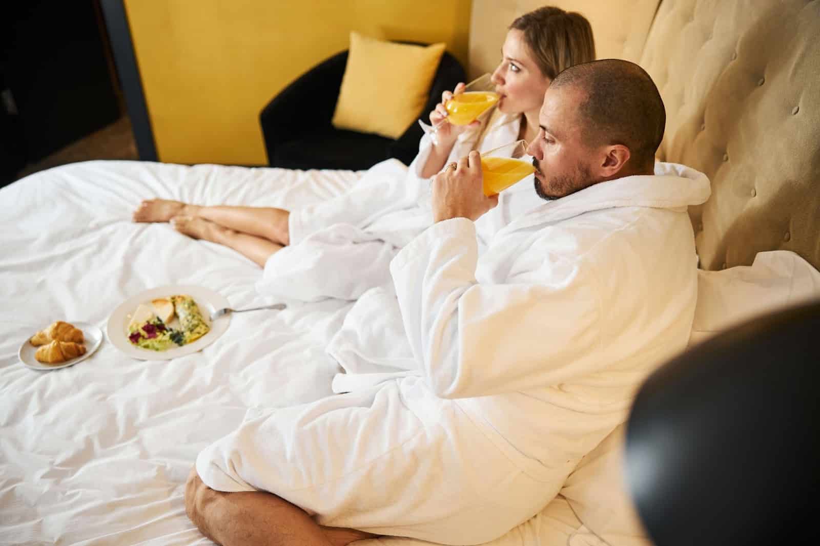 A man and woman having a breakfast together at bed.