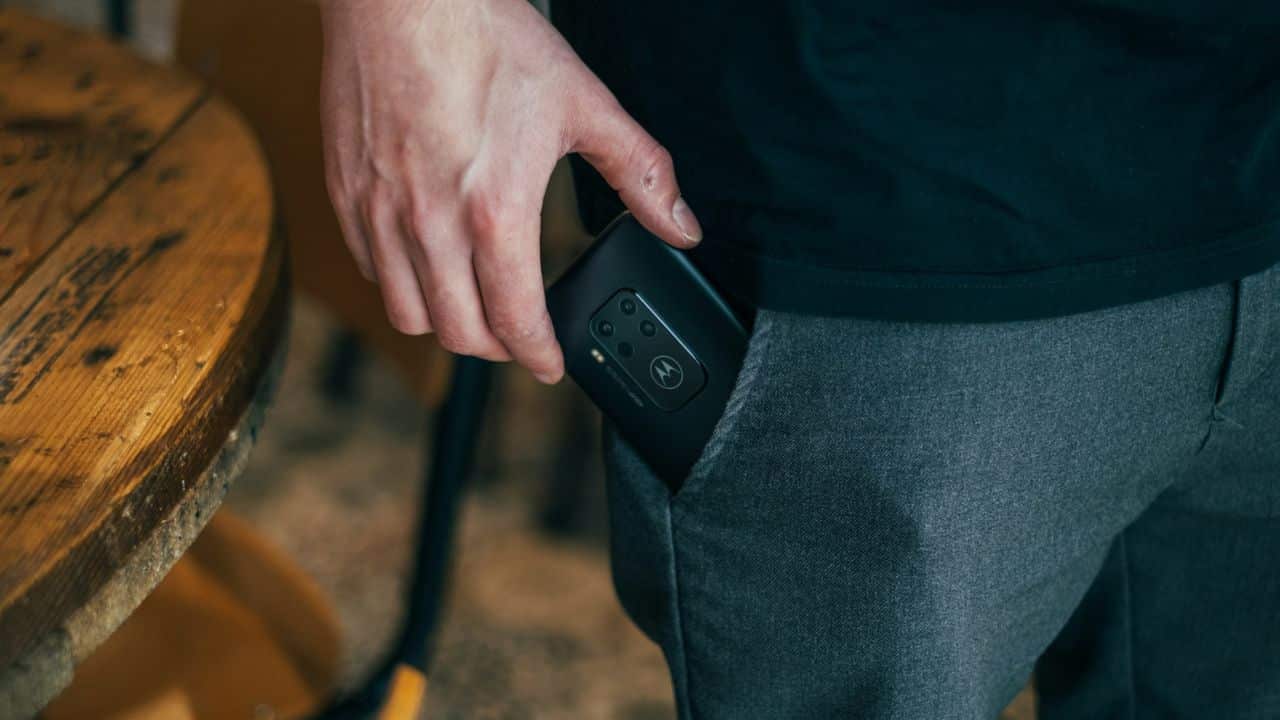 A person's hand slides a phone into their front pocket.