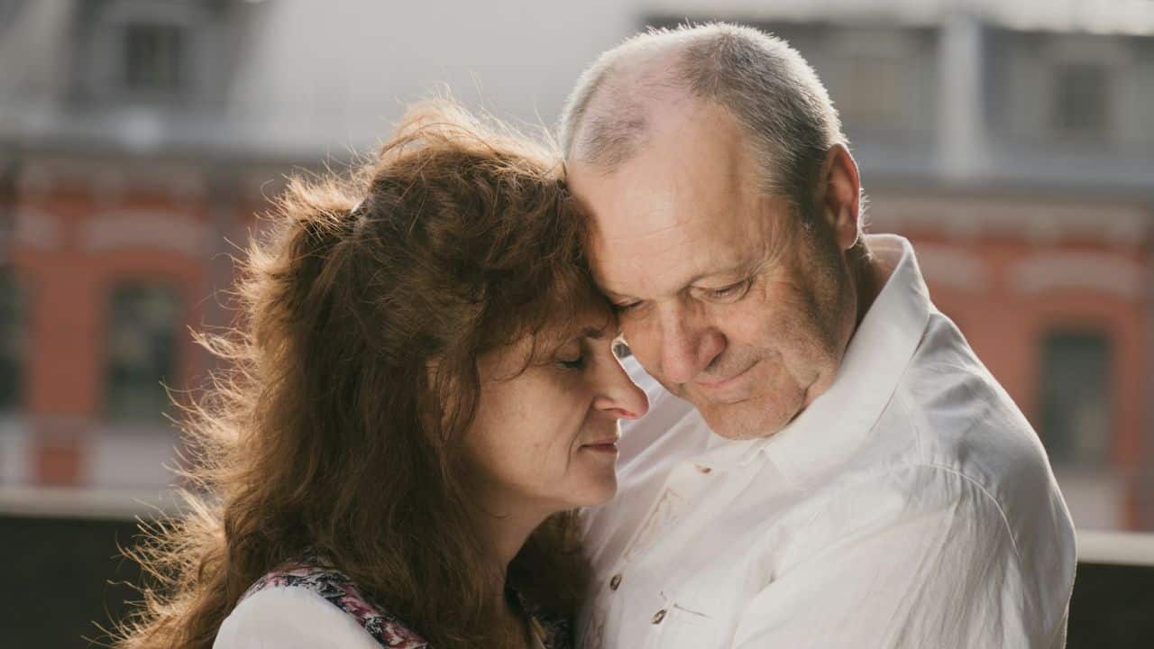 A couple with their eyes closed presses their foreheads together.