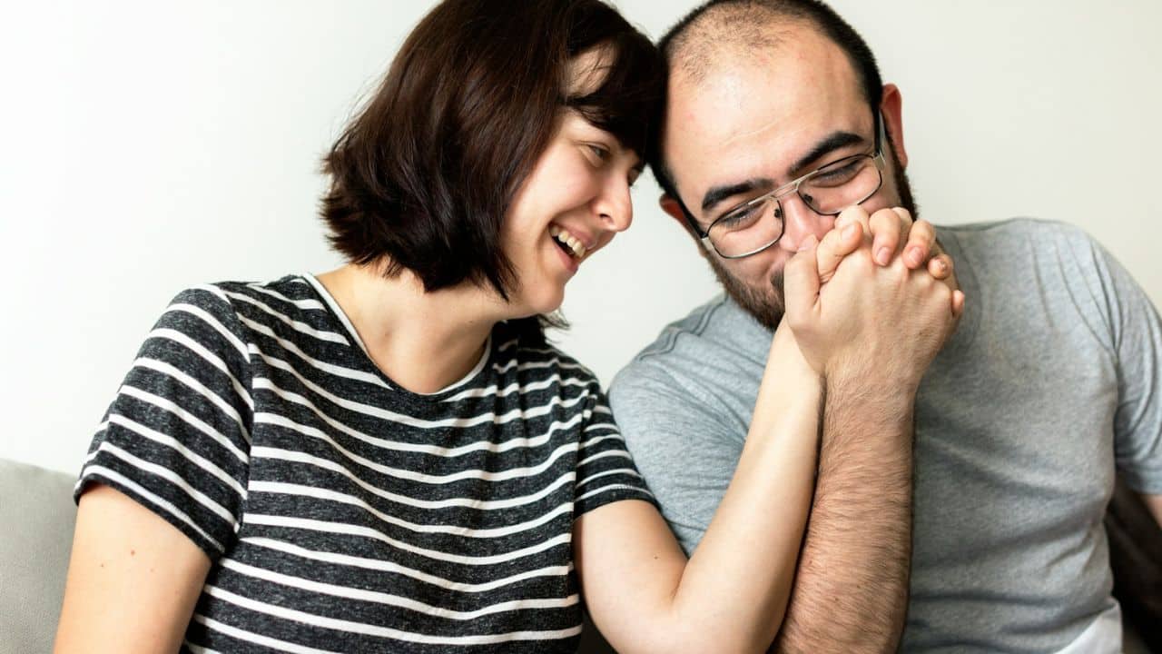 A happy couple laughs together while holding hands.