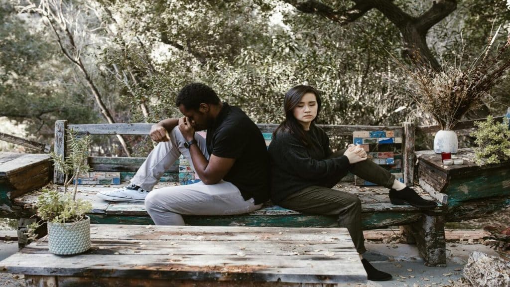 A couple sitting sadly on a bench