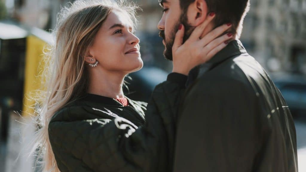 A young couple looks lovingly at each other while embracing outdoors.