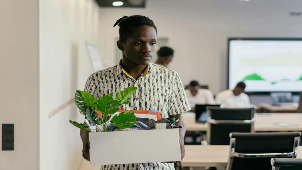 A man looking sad while carrying a box.