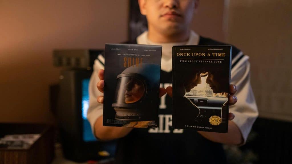 A man holding up two video tapes.