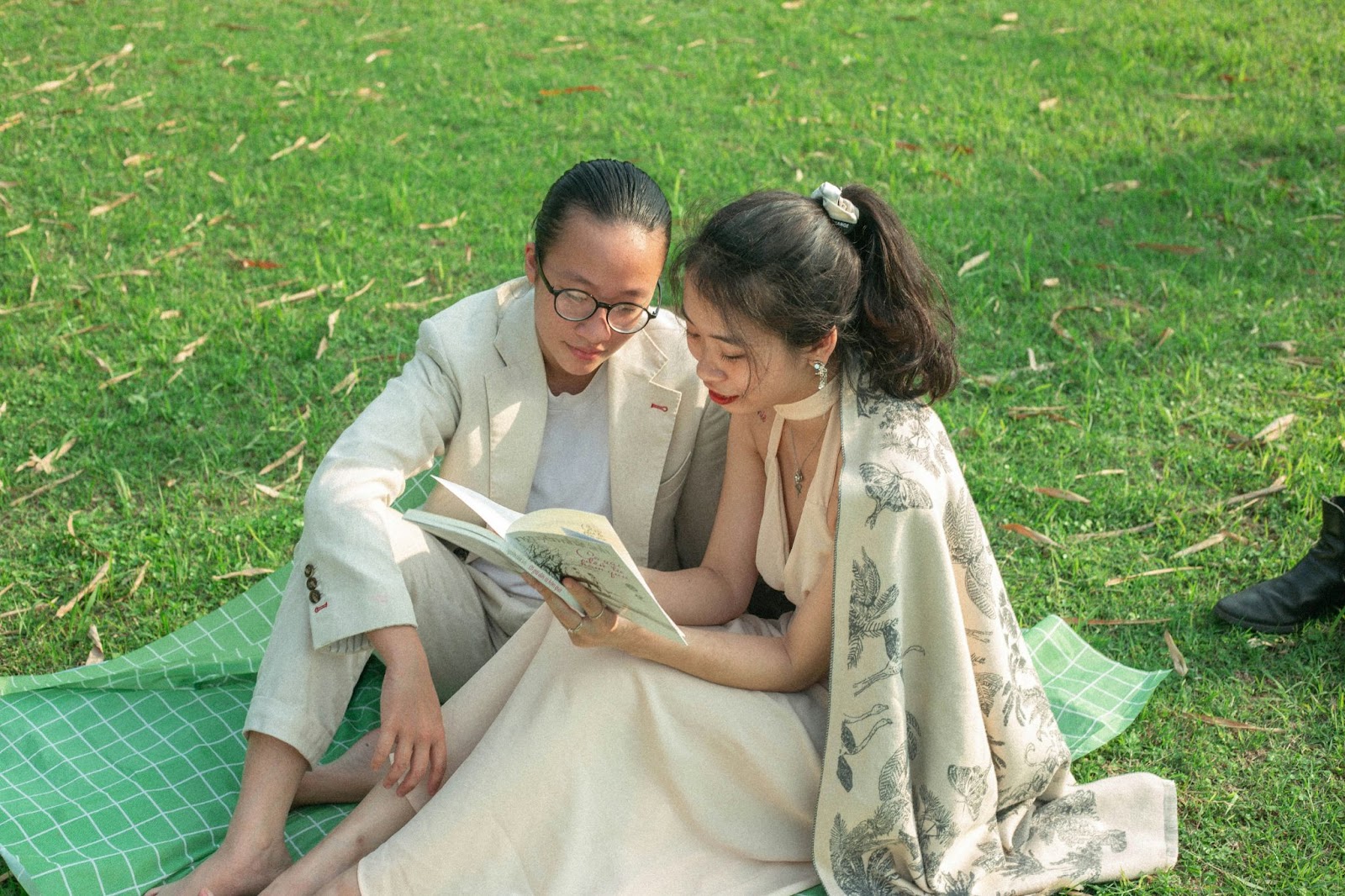 A man and woman reading a book at the park.