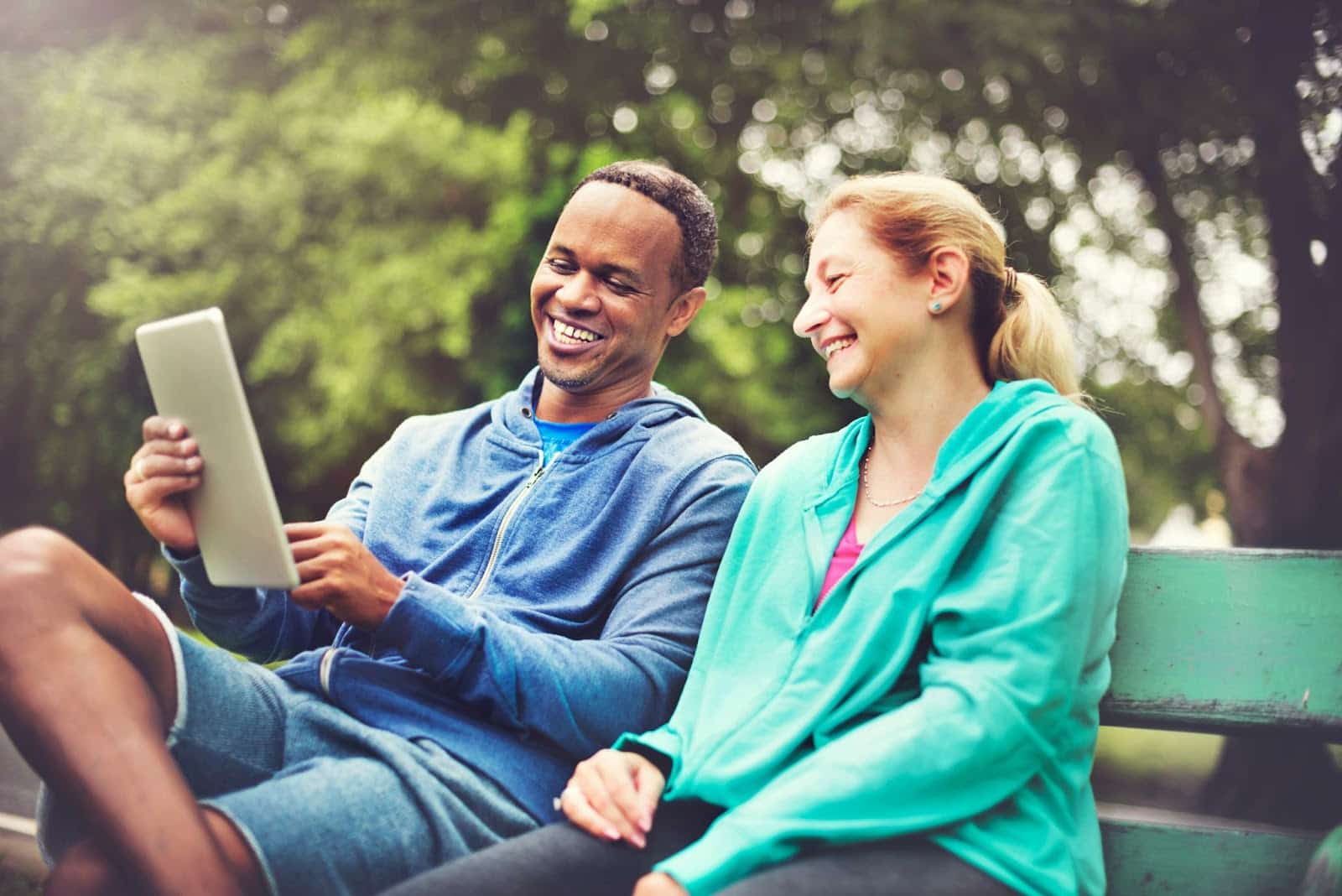 A man showing something and a woman laughing at it.