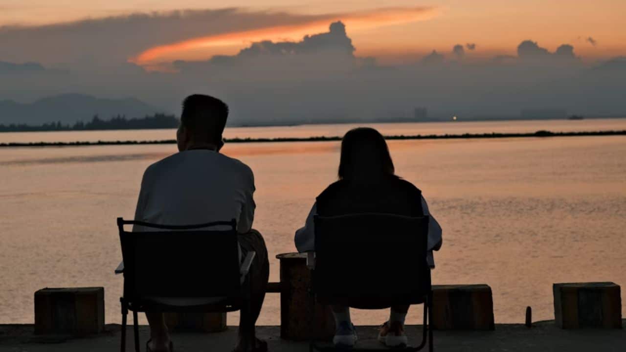 Couple sitting on a bench waiting for the sunset.