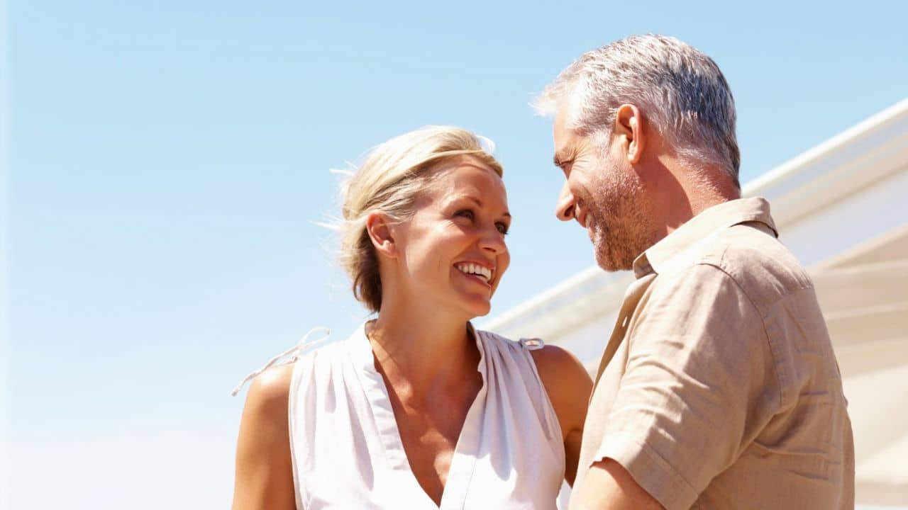 A couple is looking and smiling at each other in the sun.