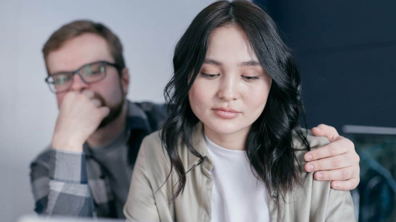 Man sincerely apologizing and holding her partners shoulder.