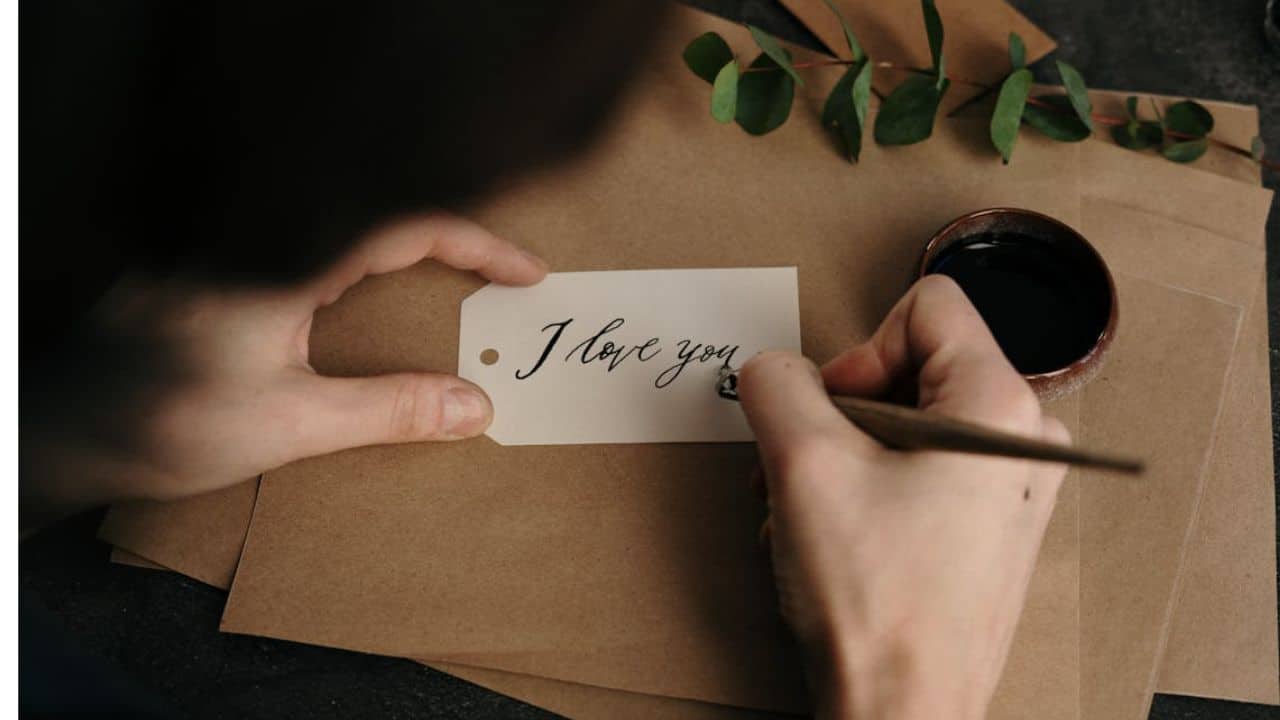 Person holding white print paper with the words I love you written on it.