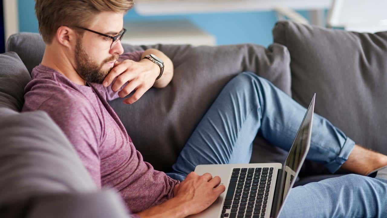 A man sitting on a couch using a laptop.