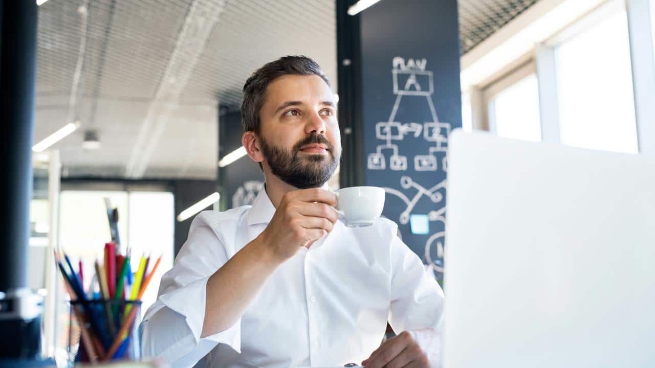 A man drinking coffee at his desk.