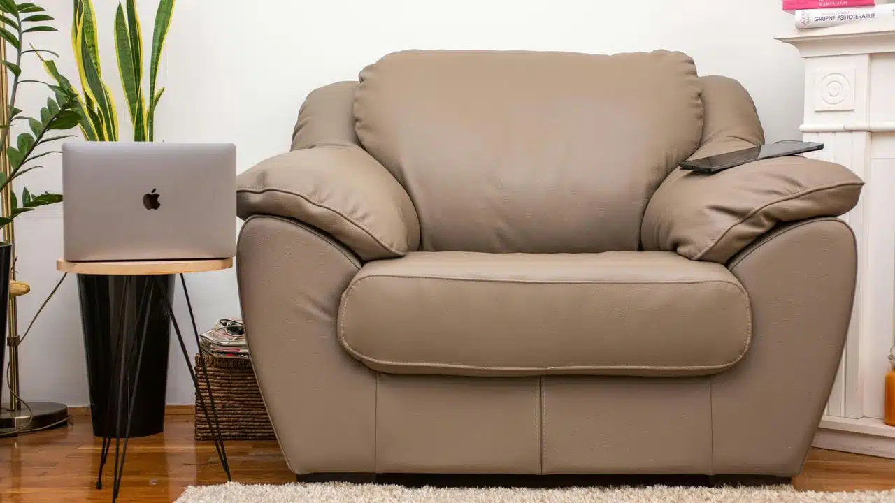 A beige armchair with a laptop and phone.