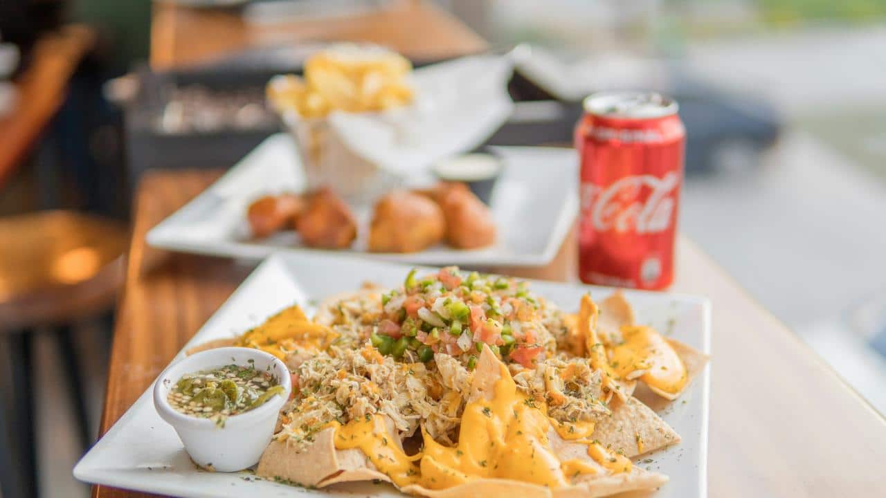 A plate of nachos with a can of soda.
