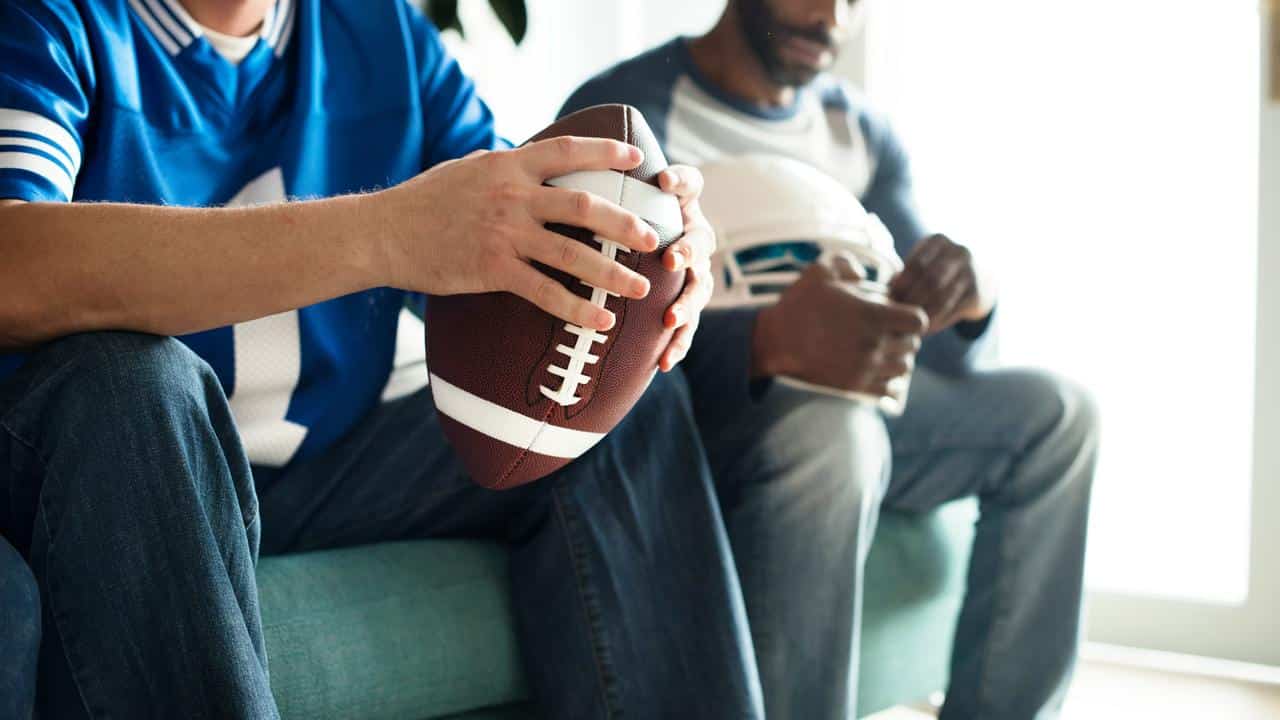 A man holding a football next to another with a helmet.