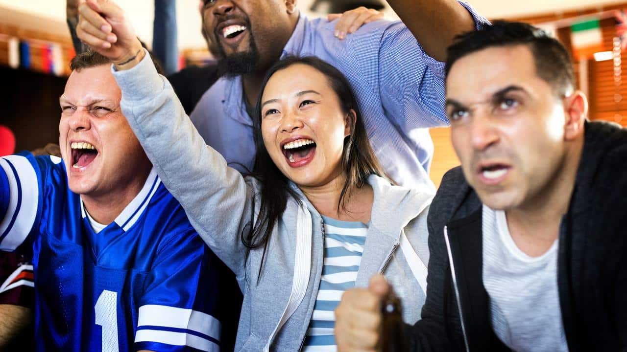 A group of friends cheering while watching a game.