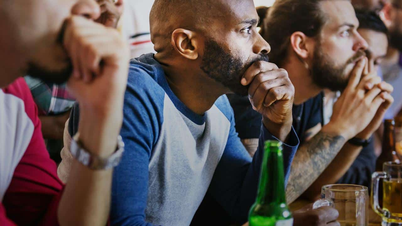 A focused group of men watching an intense game at a bar.