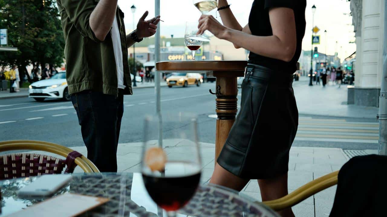 A couple with wine glasses at an outdoor table.