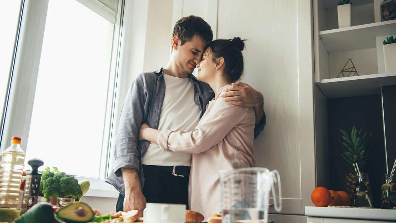 A couple embracing in a kitchen.