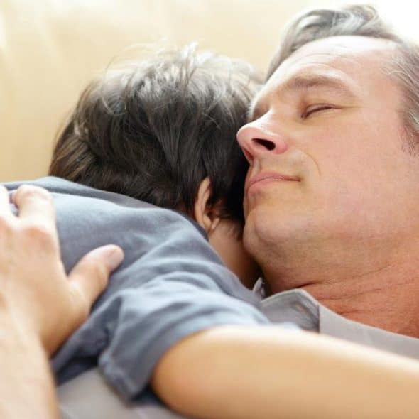 A man and child resting together on a couch.