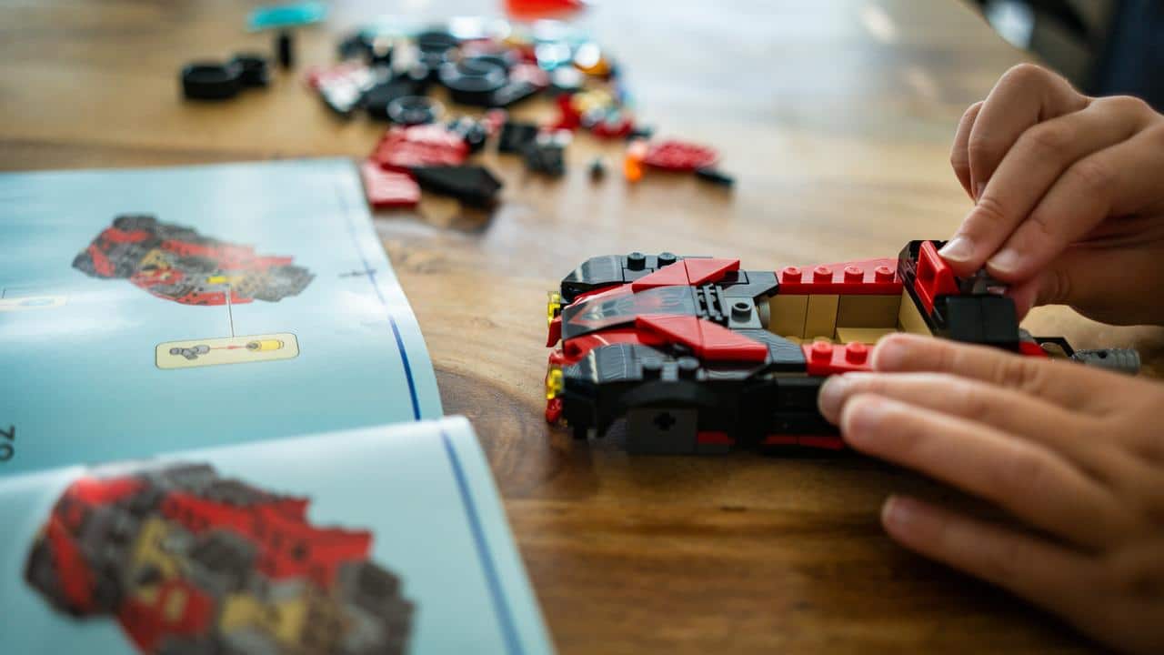 A child assembling a toy car with building blocks using instructions.