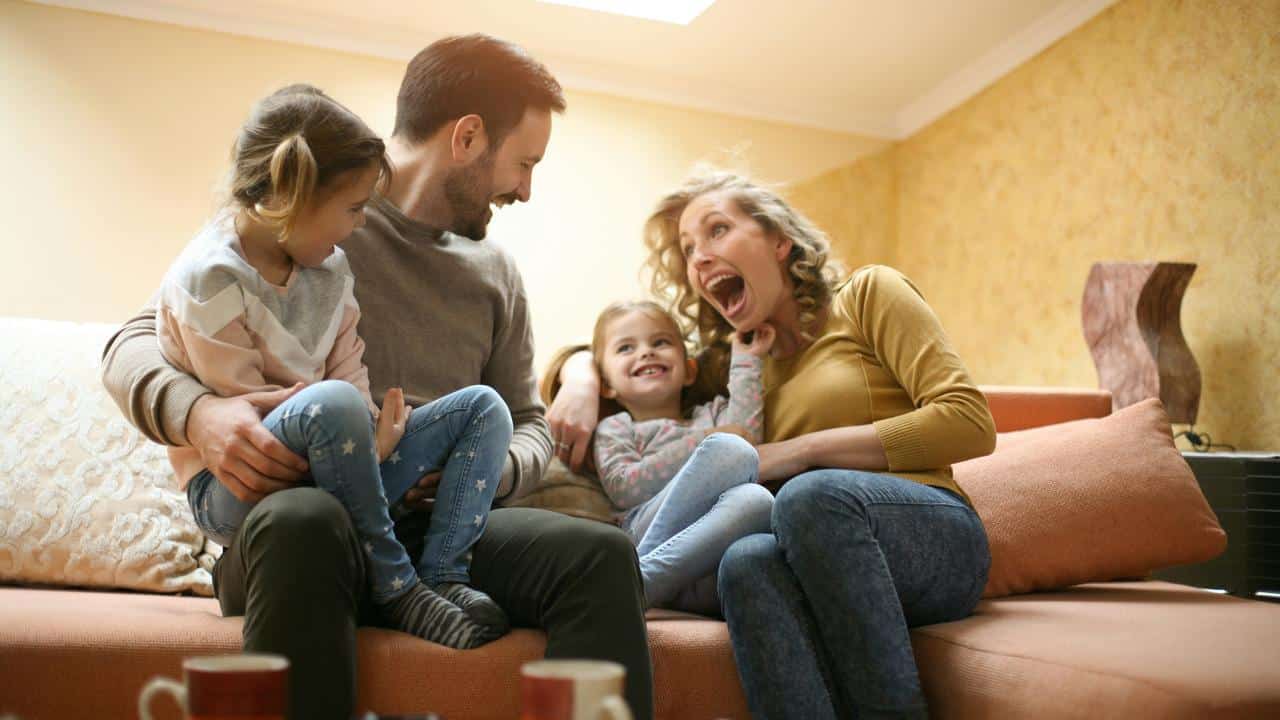 A family sitting on a couch laughing and playing together.