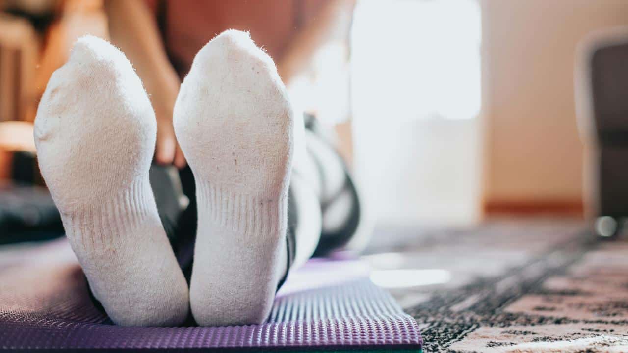 A person lying on a yoga mat wearing white socks.