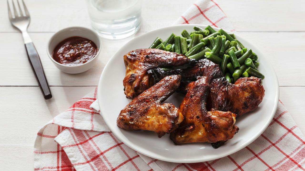 A plate of grilled chicken wings with green beans.