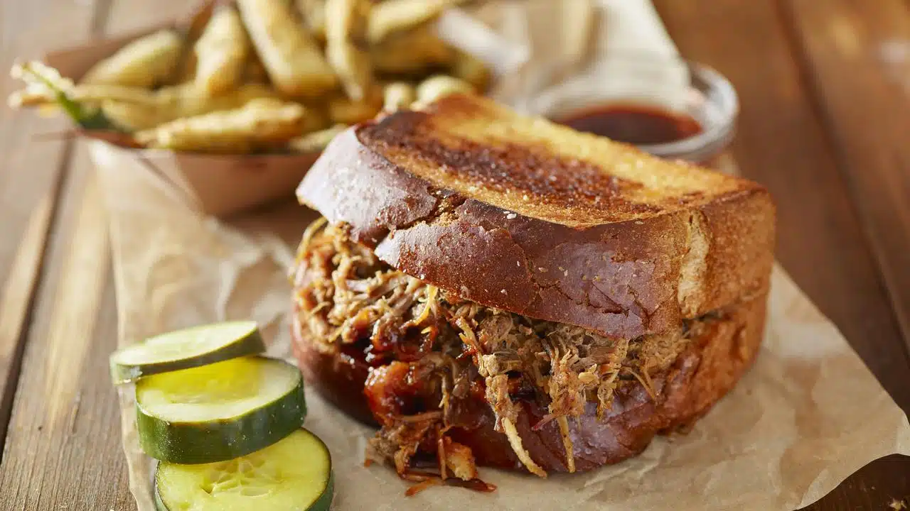 A pulled pork sandwich with pickles.