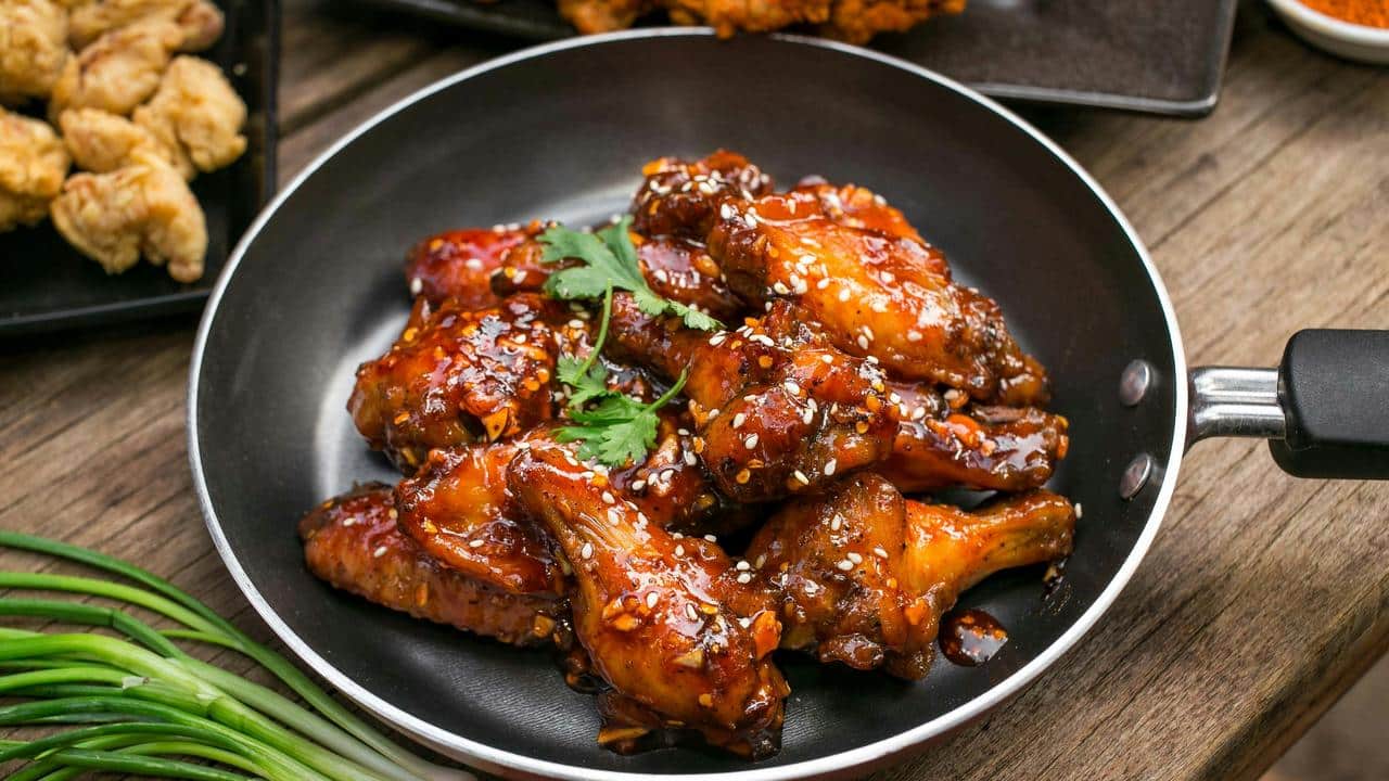 A pan of glazed chicken wings with sesame seeds.