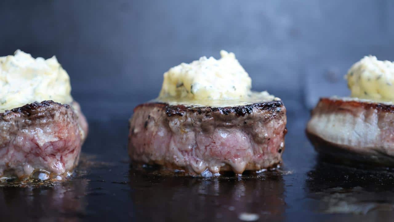 A close-up of steak topped with melting butter.