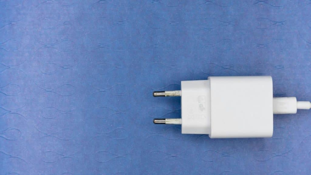 A white phone charger on a blue surface.