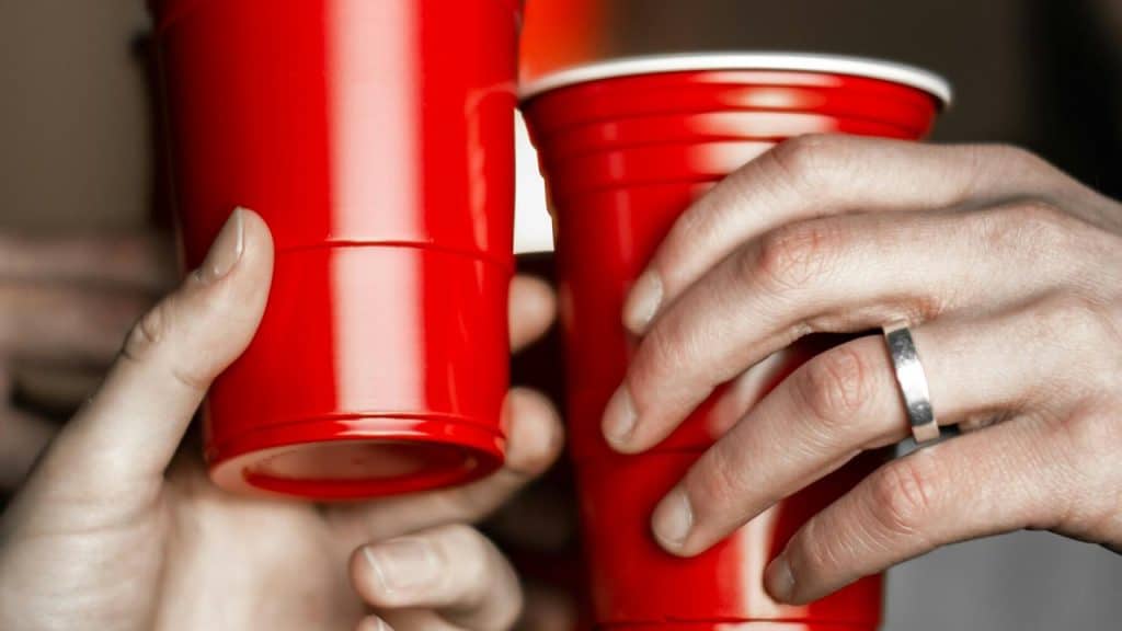 A close-up of hands holding red plastic cups.