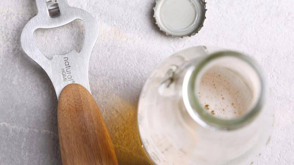 A bottle opener and opened beer bottle.