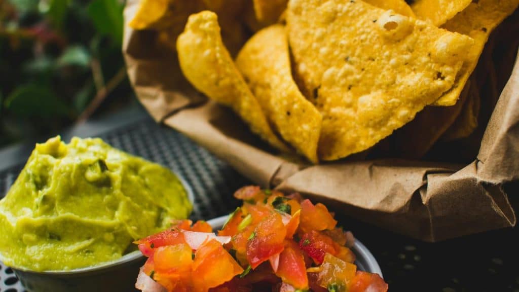 A close-up of chips with guacamole and salsa.