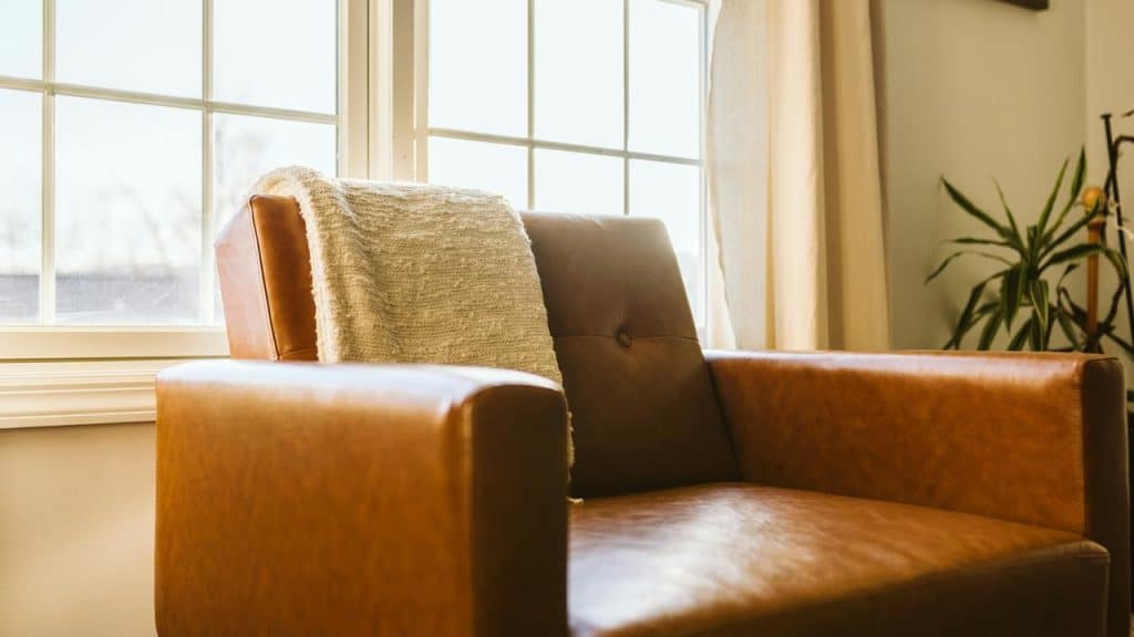 A brown leather chair by a window.